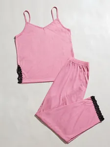 Dettaglio del set pigiama con canotta rosa e pantaloni con pizzo nero su sfondo bianco.