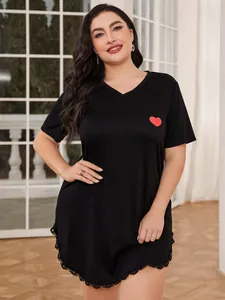 Close-up detail of plus size black nightgown with red heart motif and lace hemline