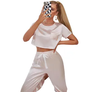 Detail of pink satin pajama set featuring a short sleeve crop top and matching trousers.