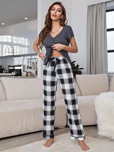 Women's pajama set featuring a grey short sleeve top and black plaid pants in a living room.