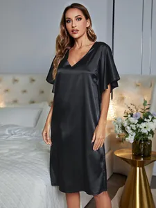 Full-length view of an elegant black satin nightgown with V-neck in a bedroom setting