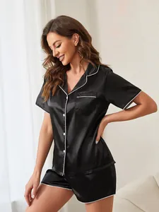 Close-up of black satin short-sleeved pajama set with white contrast piping details