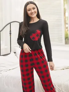 Women's pajama set featuring a black heart top and red plaid long pants in bedroom