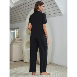 Schwarzes Damen-Pyjama-Set mit kurzen Ärmeln und langer Hose im gemütlichen Raum