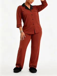 Elegant terracotta pyjamaset met lange mouwen, zwarte reverskraag en bijpassende broek.