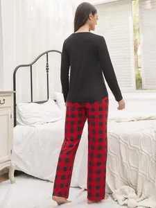 Back view of women's long sleeve red and black plaid pajama set in a cozy bedroom setting