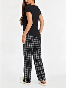 Detailed back view of woman wearing black short-sleeved top and plaid pajama pants