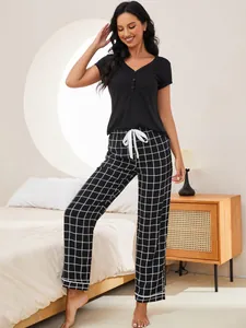 Detailed view of women's two-piece nightwear set featuring black top and plaid long pants