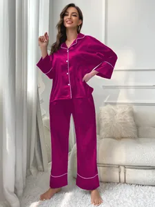 Elegant fuchsia satin pajama set for women with white piping detail in home setting