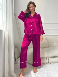 Detail of elegant fuchsia satin pajama set featuring long sleeves and white piping