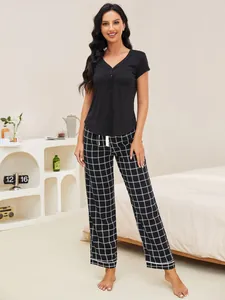 Full-body view of a stylish women's black short-sleeve top and plaid pajama set
