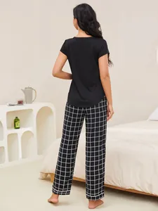 Back view of women's short sleeve pajama set featuring a black top and stylish plaid pants