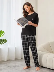 Lifestyle-Detail des schwarzen Damen-Pyjamas mit Herzprint und karierter Hose Set