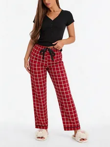 Detailed view of women's two-piece pajama set featuring black V-neck top and red plaid pants