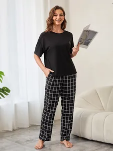 Damen-Schlafanzug-Set mit schwarzem Kurzarm-Oberteil und karierter Hose in Wohnumgebung