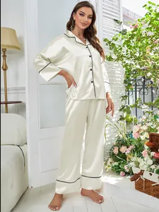 Full length view of elegant cream satin pajama set with black contrast piping details.