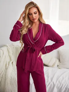 Elegante pigiama da donna rosso vino con profili bianchi, top a vestaglia e pantaloni lunghi.