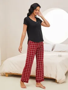 Full view of woman wearing black V-neck pajama top and red checkered pants set
