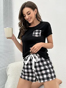 Mujer con pijama negro de manga corta con bolsillo y pantalones cortos de cuadros y corazones