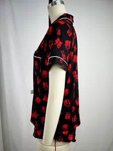 Side view of women's black pajama set with red gift box print and white piping detail.