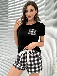 Mujer con camiseta negra y conjunto de pijama de cuadros con corazones en su hogar