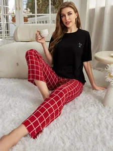 Lifestyle-Foto einer Frau in einem schwarzen T-Shirt und einer rot-karierten Pyjamahose