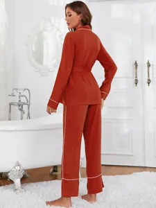 Vista posteriore di elegante pigiama da donna rosso terracotta con profili bianchi