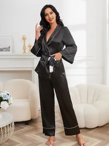 Detailed view of black satin pajama set for women, long sleeves and pants in a home setting.