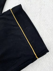 Macro-opname van de elegante gele bies op de zwarte stof van deze luxe pyjama