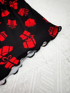 Close-up of women's pajamas lettuce edge hem with red gift box print on black fabric