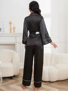 Back view of elegant black silk pajama set with white piping and belted waist detail