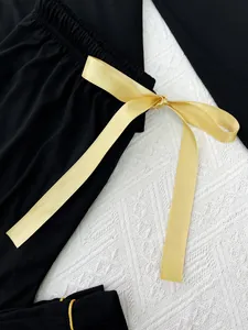 Detail van een gouden satijnen strik op de elastische tailleband van een zwarte pyjamabroek