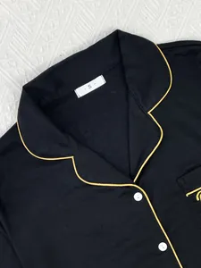Detail van de zwarte damespyjama met gele bies en witte knopen voor een luxe uitstraling