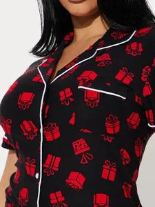 Close-up of black women's pajama top with festive red gift box prints and white piping