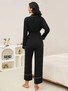Elegante vista posteriore del set pigiama nero a maniche lunghe da donna con bordino bianco e cintura