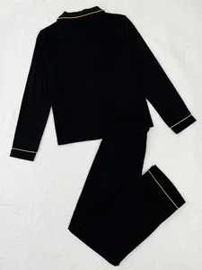 Gedetailleerd overzicht van zwarte pyjamaset met lange mouwen en elegante gouden biezen.