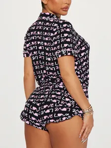 Close-up detail of black short-sleeve pajama set featuring pink heart and love print patterns.