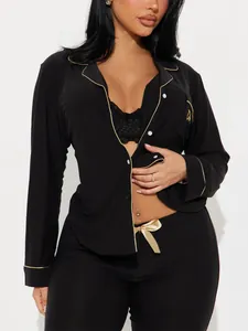 Detailweergave van zwarte pyjamaset met lange mouwen, gouden bies en borduursel