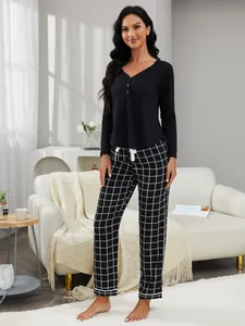 Pigiama da donna in due pezzi con maglia nera a maniche lunghe e pantaloni a scacchi bianchi.