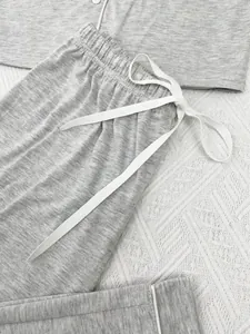 Detail macro view of gray pajama pants showing the white drawstring and elastic waistband