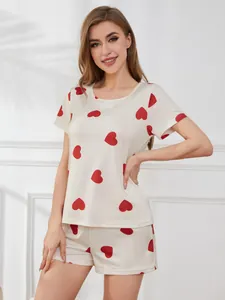 Female model showcasing a cream-colored summer pajama set with vibrant red heart prints.