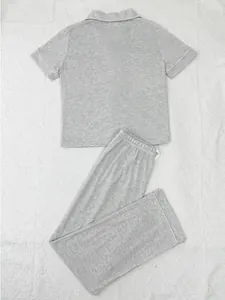 Detailed view of gray short sleeve pajama set with white piping on textured background