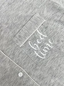Close-up of heather gray pajama pocket with 'Bed time' print and button detail.