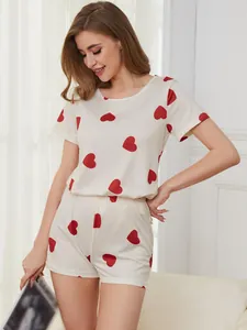 Woman wearing a comfortable white summer pajama set featuring cute red heart prints