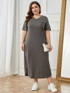 Graues Plus-Size-V-Ausschnitt-Kleid mit Taschendetail an Model im Schlafzimmer.