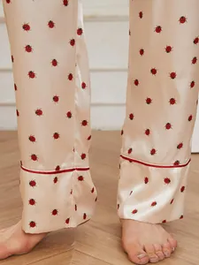 Primo piano dettagliato dei pantaloni del pigiama in seta con stampa a coccinella e profili rossi