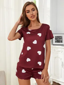 Female model wearing a burgundy heart print pajama set with short sleeves and shorts
