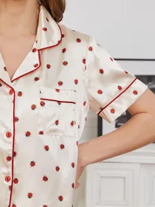 Dettaglio della maglia del pigiama in raso da donna con stampa a coccinelle rosse.