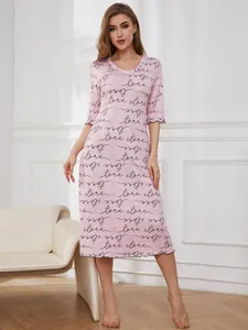 Elegant pink nightgown with letter print, modeled in a bright home interior setting.