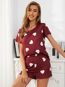 Woman wearing burgundy heart print pajama set in a bright modern bedroom setting